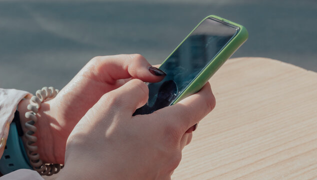 Phone In The Hands Of A Woman With A Black Dirty Screen In A Cafe On The Street.