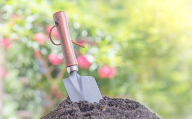 Metal trowel digging soil with blurred green background, Hand shovel for the gardening