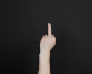 A woman's hand shows fack you. Middle finger on a black background.