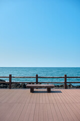 Obraz na płótnie Canvas A wooden deck and bench overlooking the vast ocean horizon.