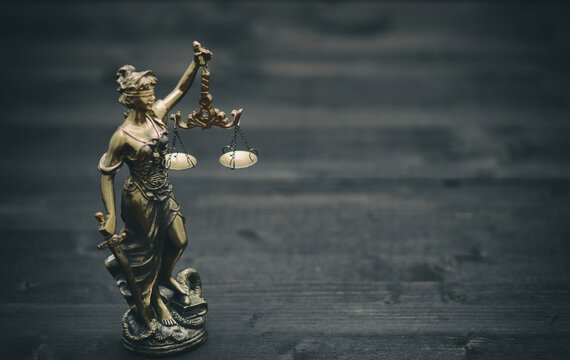 Scales of Justice, Justitia, Lady Justice on a black wooden background.