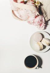 top view of pink macaroons with roses and coffee on white background with copy space