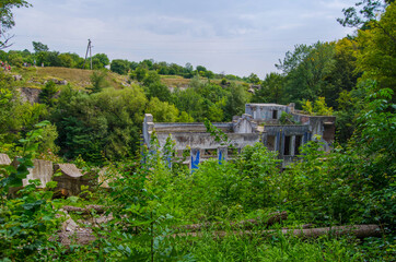 Fototapeta na wymiar An old building of the power station among green trees, Buky Canyon Ukraine, the Hirskyi Tikych river, the Cherkasy Oblast