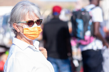 Senior woman with protective face mask at flea market looking for some opportunity