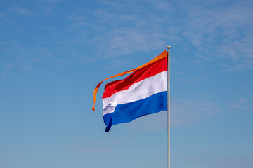 National holiday King’s Day or Koningsdag in Dutch, Due to Coronavirus disease (COVID-19) scourge, Celebrations will not take place this year, Netherlands and orange flag in the air with blue sky.