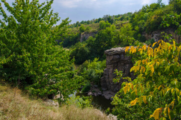 Fototapeta na wymiar The river flows in a stone canyon among the green trees, Buky Canyon Ukraine, the Hirskyi Tikych river, the Cherkasy Oblast