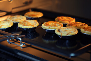 Mini pie from meat and mushrooms baking in industrial oven