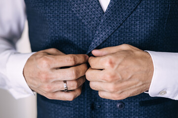 men's hands close-up, the groom prepares in the morning before the wedding ceremony, puts on a vest from a suit.