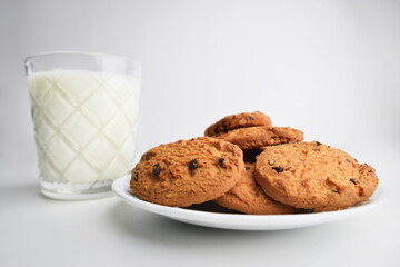 Food, baking and eating concept - close up of chocolate oatmeal cookies and milk glass on plate. 
