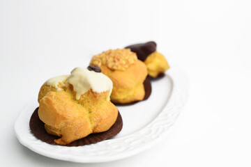 Cream puffs on a plate. French pastry with cream and chocolate sauce. Italian sweet profitterol.