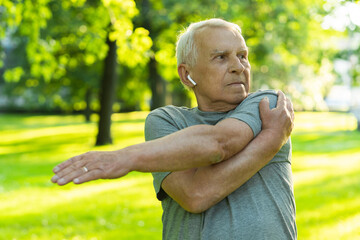 Elderly man exercising in green city park during his fitness workout