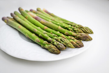 Asparagus. Green Asparagus. Bunches of green asparagus on the white plate. Green asparagus sticks isolated on white background. Background with copy space.