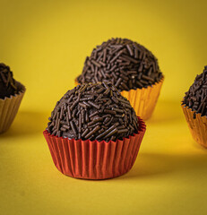 Traditional brazilian chocolate candy called "Brigadeiro" on yellow background.