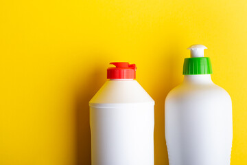 bottles with detergents set on a yellow background. means to maintain cleanliness in the house.