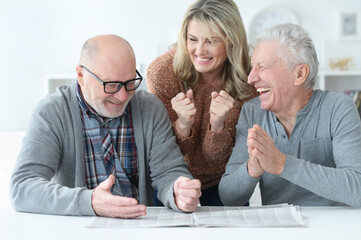  senior people  sitting at table and reading newspaper