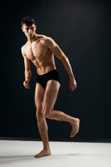 Obraz premium man in black panties with naked muscular body posing against dark background
