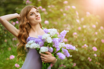 Fototapeta premium portrait of beautiful young woman posing with lilacs