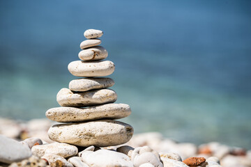 Pebbles stack balance over blue Adriatic sea in Croatia. Blue sky and water on sunny coast in summer