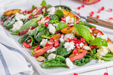 Salad. Spring vegetable salad. Fresh vegetable salad with grilled peach, pomegranate, spinach and fresh cheese.