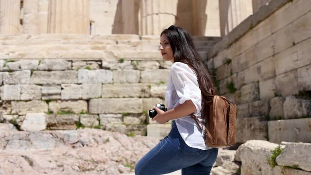 A tourist woman on summer vacations walks up to the Parthenon Temple at the Acropolis of Athens, Greece