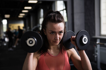 Close up of a focused female athlete exercising with dumbbells