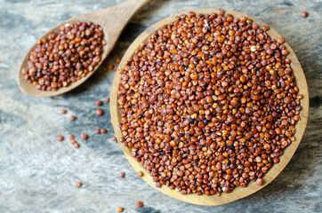 Top view of dry organic red quinoa seeds in wooden bowl on grunge wooden background