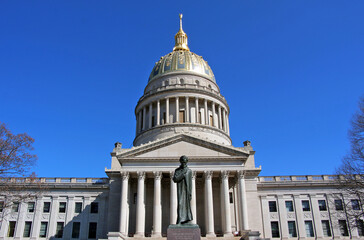 The West Virginia Capitol glows in the sun with the Abraham Lincoln statue in the foreground.