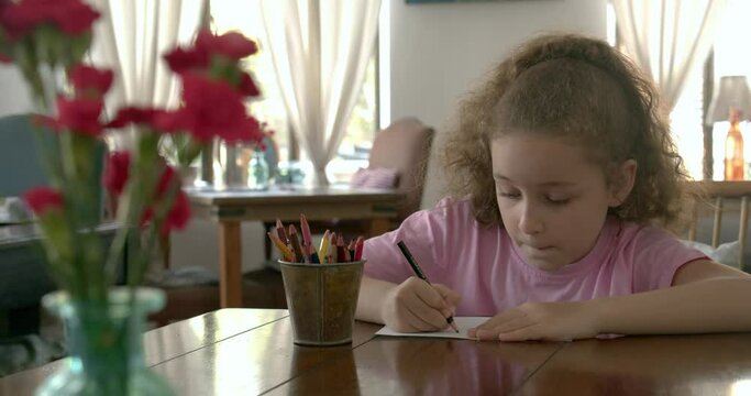 Happy Little Girl or Cute primary child school child of 7-8 years old at home relaxing sits in house and paints on paper use colour pencils. Child draws,focused children elementary education concept.