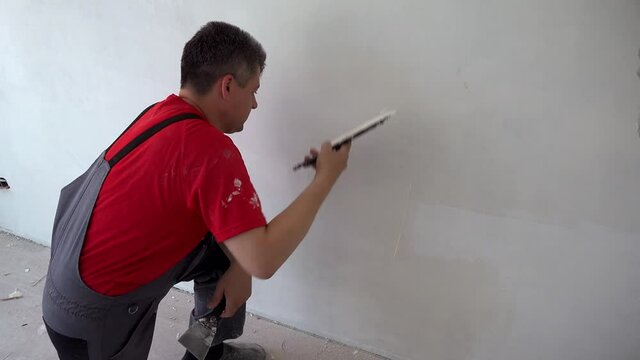 Construction specialist man spackling wall with trowel.