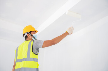 Young worker paints walls in a creative home, house painter.