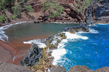 Volcanic black rocks secure the beautiful red sand beach from the breaking waves, Maui, Hawaii,...