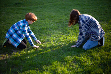 Boy and girl teenagers on their knees looking for something in the grass