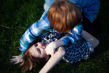 Boy and girl teenagers are fighting on the grass in nature