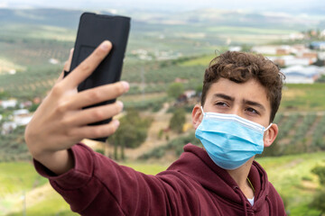 young teenager taking a picture with a smartphone while wearing a mask
