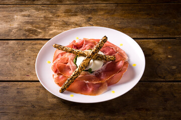 plate with San Daniele raw ham and buffalo mozzarella from Campania on wooden table