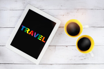 Travel word on rainbow flag on computer tablet with cups of coffee on table. Lesbian gay bisexual transgender concept and equality diversity idea