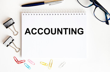 In the notebook, the text is ACCOUNTING, next to paper clips, paper clips, glasses and pen, reports and diagrams.