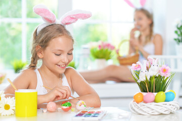 Obraz na płótnie Canvas sisters wearing rabbit ears decorating Easter eggs