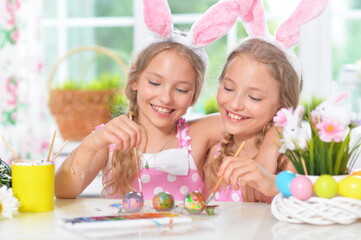 Obraz na płótnie Canvas Cute twins wearing rabbit ears decorating Easter eggs