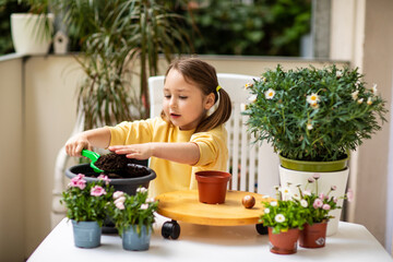 Little girl planting flowers on the balcony
