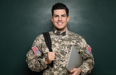 Cadet with backpack and laptop near chalkboard. Military education