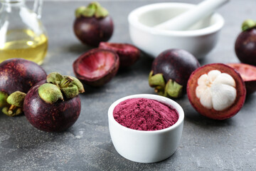 Purple mangosteen powder and fruits on grey table