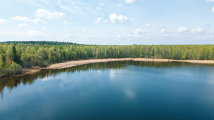 Beautiful summer landscape, calm surface of the lake, forest, sandy shore. The clouds are reflected in deep water. Ideal for fishing and hiking. Aerial photography, drone view. Digital detox.