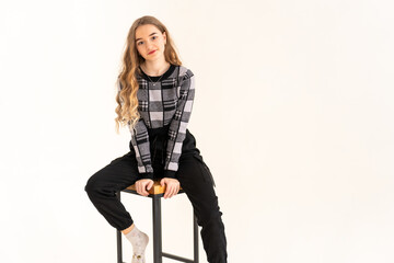 Beautiful young girl sitting on a chair in the studio