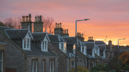 Fototapeta na wymiar A row of traditional British terraced houses or townhouses during a vibrant, colourful sunset or sunrise in the neighbourhood of Liberton, Edinburgh, Scotland, UK.