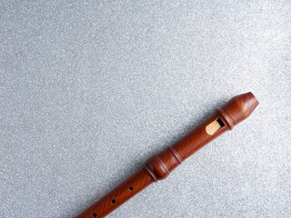 Top view of a wooden baroque recorder or flute, isolated on a shiny silver background, with copy...