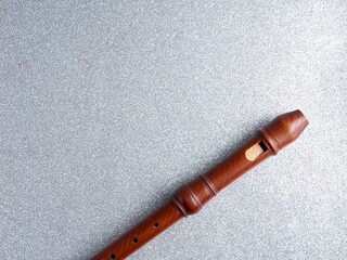 Top view of a wooden baroque recorder or flute, isolated on a shiny silver background, with copy space © Novodiastock