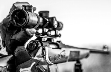 Hunter man. Hunting period. Male with a gun. Close up. Hunter with hunting gun and hunting form to hunt. Hunter is aiming. The man is on the hunt. Hunt hunting rifle. Black and white