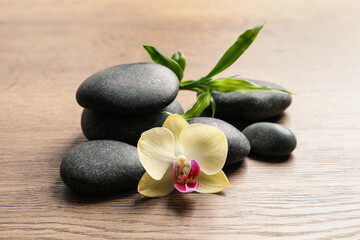 Obraz na płótnie Canvas Spa stones, beautiful orchid flower and bamboo sprout on wooden table