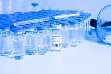 Vaccine vials and syringes containing COVID 19 cure. Ready to administer the shot. Medical research against Coronavirus. Drugs, medications and ppe on the table of medical worker.